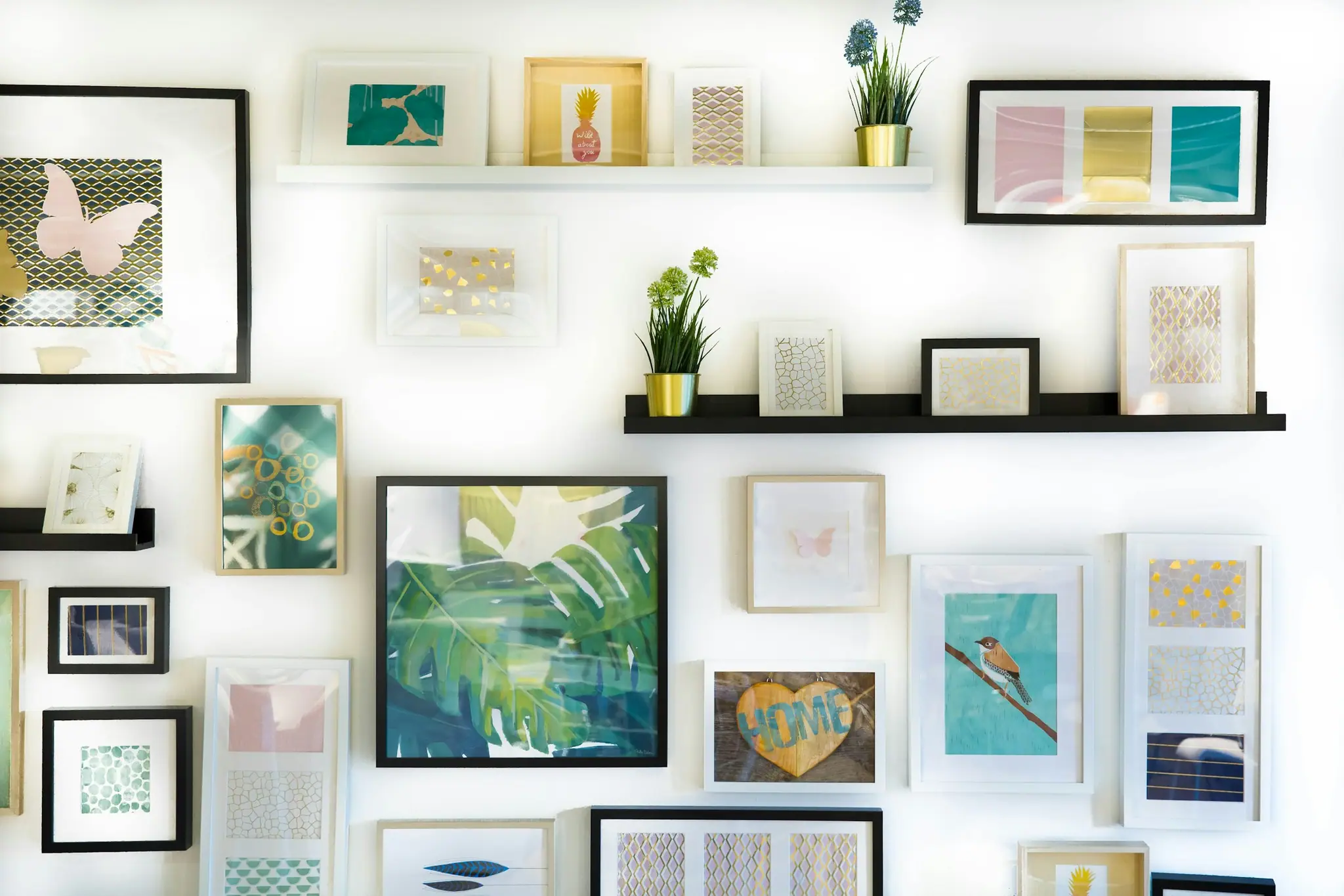 Framed prints arranged on a bright wall with shelves