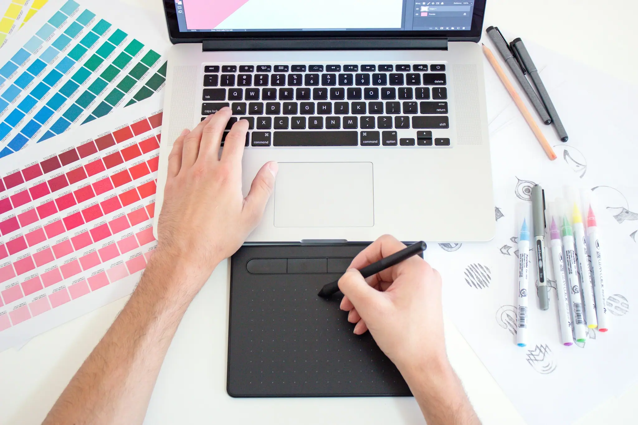 Designer sketching on a drawing tablet beside colour swatches