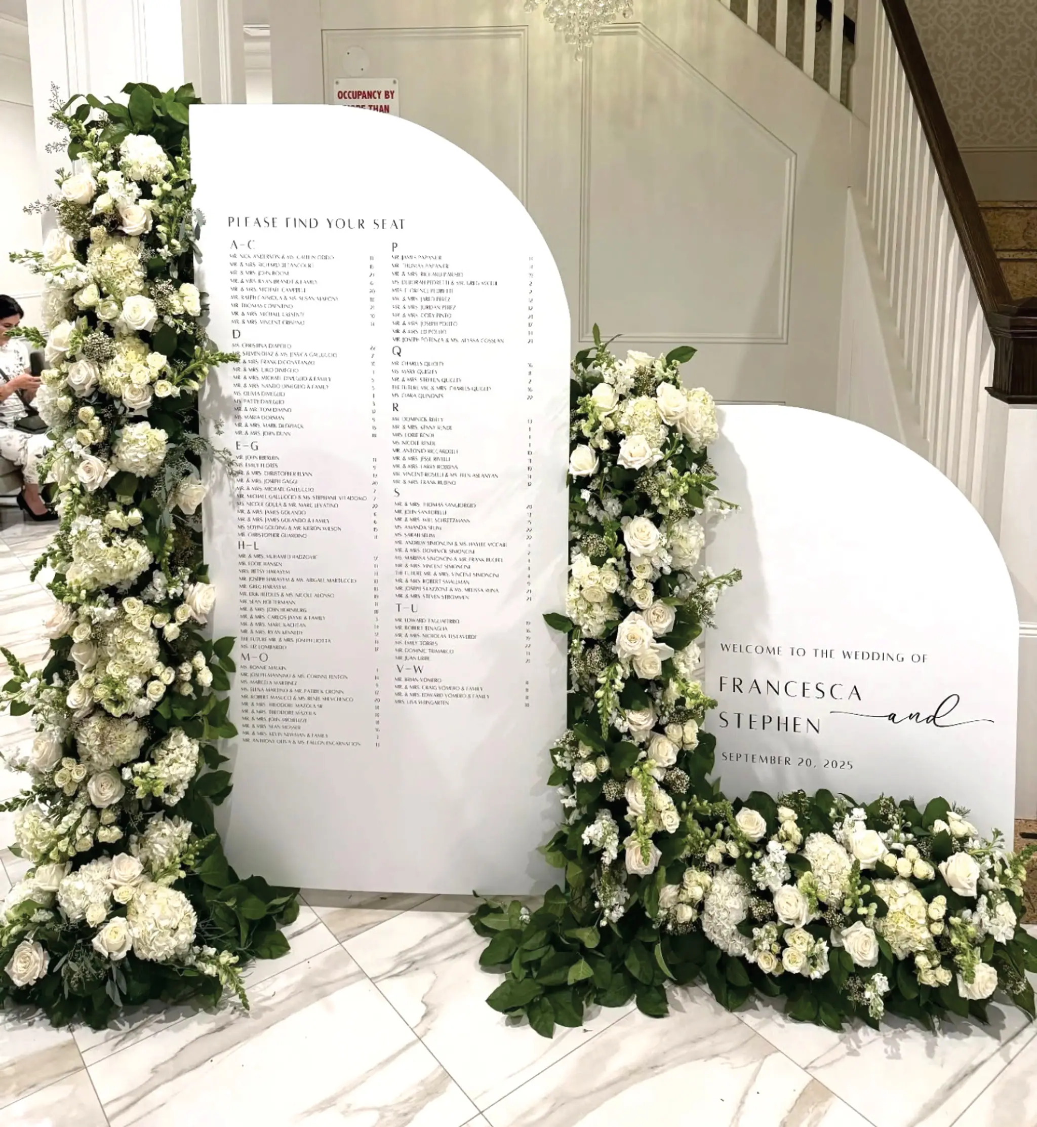 Arched seating chart and welcome signs framed with white flowers