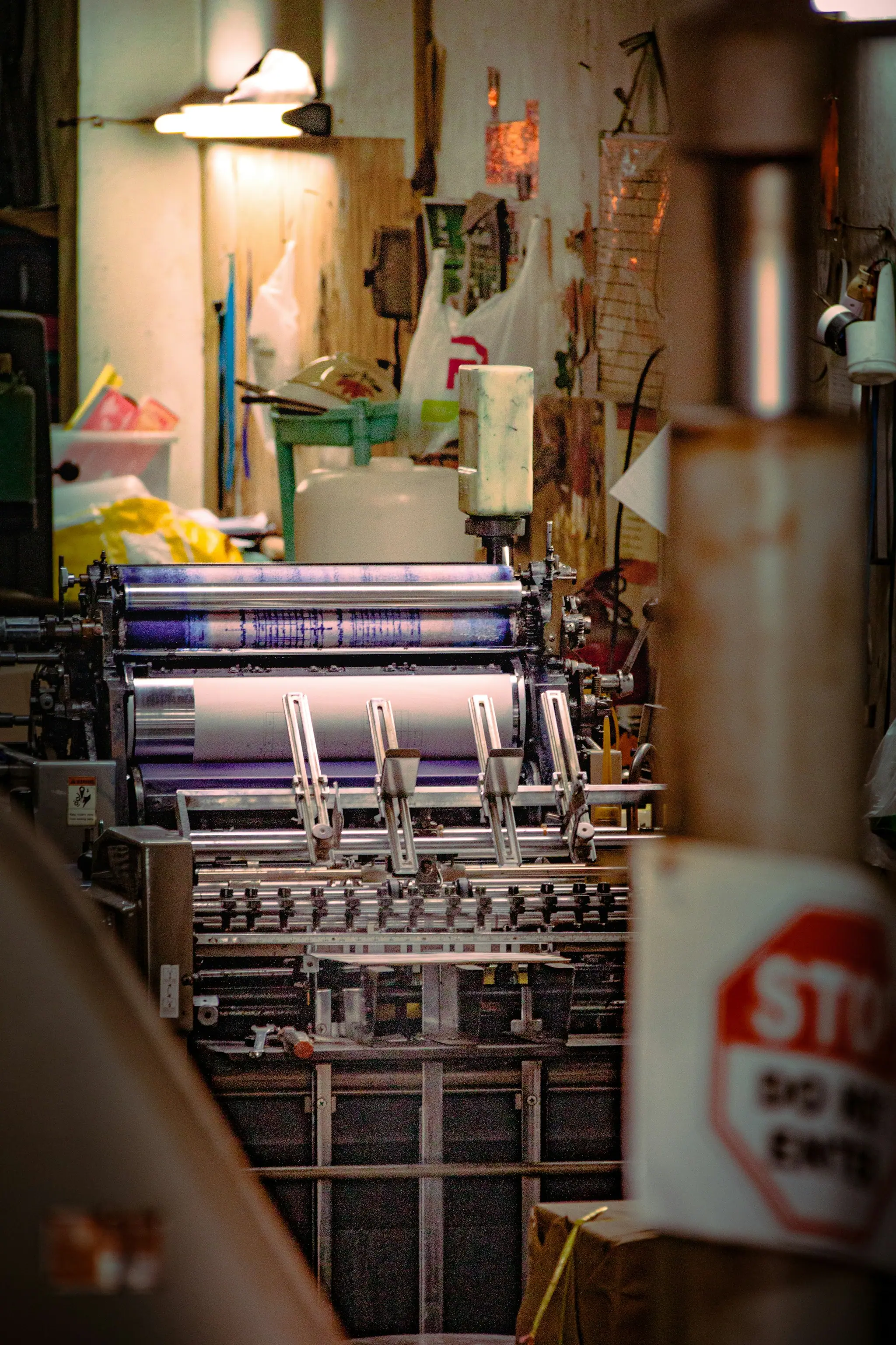 Printing press with inked rollers in a busy print shop